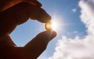 Person holding vitamin d pill up towards the sun